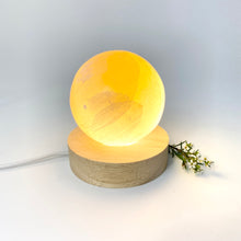 Load image into Gallery viewer, Crystals NZ: Orange selenite crystal sphere lamp on LED wooden base
